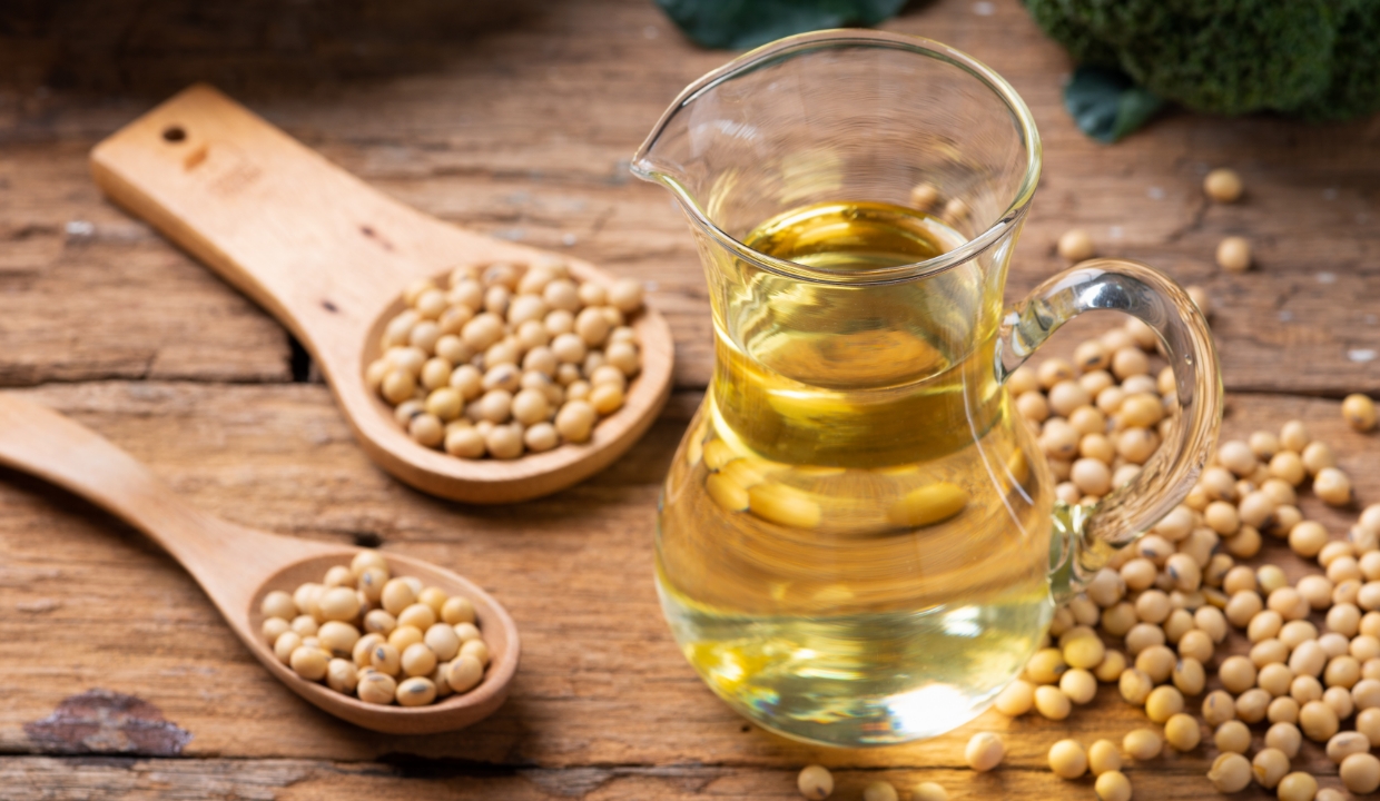 Soybeans surrounding a beaker of vegetable oil